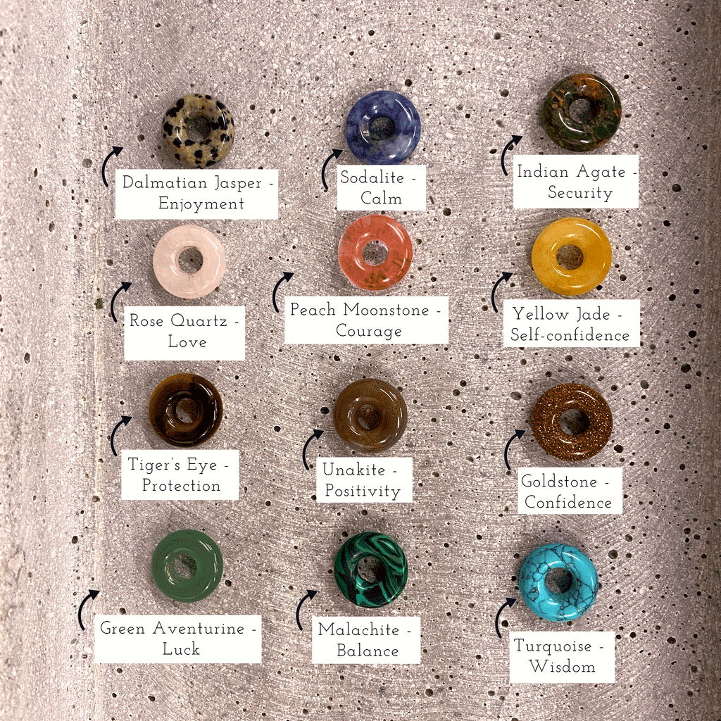 All crystal donuts displayed - dalmatian jasper for enjoyment, sodalite for calm, indian agate for security, rose quartz for love, peach moonstone for courage, yellow jade for self-confidence, tiger's eye for protection, unakite for positivity, goldstone for confidence, green aventurine for luck, malachite for balance, turquoise for wisdom